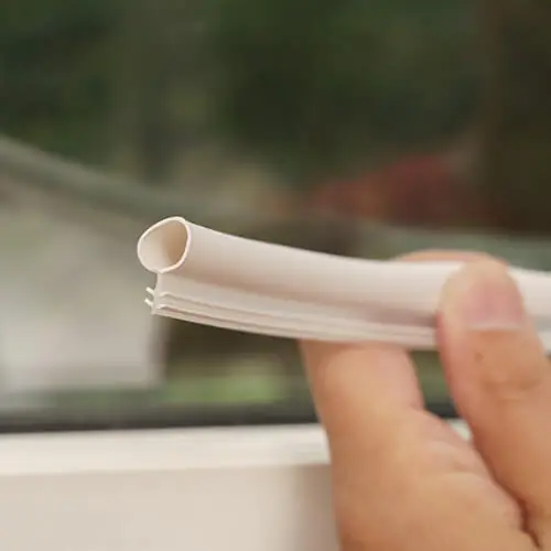 A close-up of a hand holding a piece of white bulb weatherstripping.